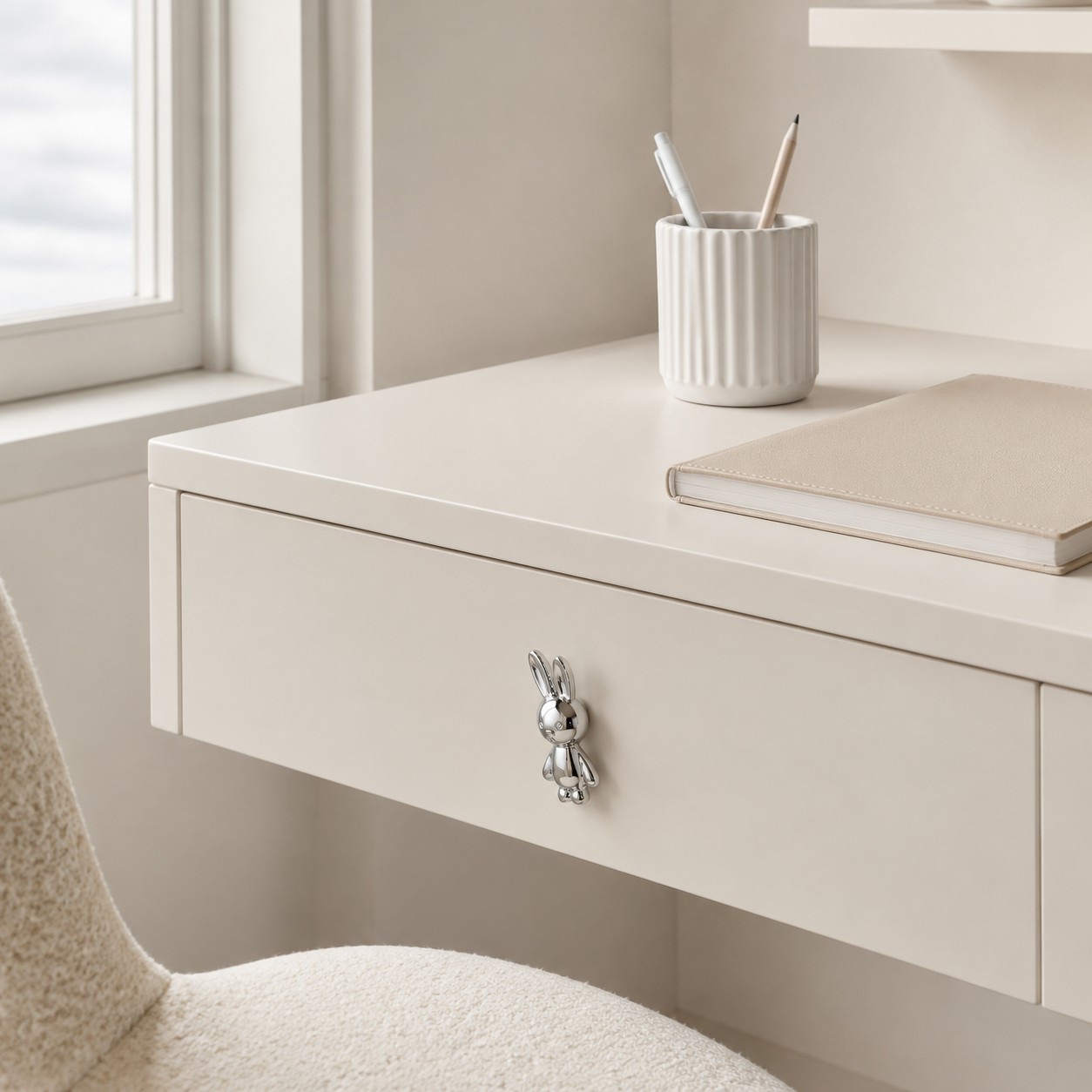 Chrome silver rabbit knob on a white desk drawer
